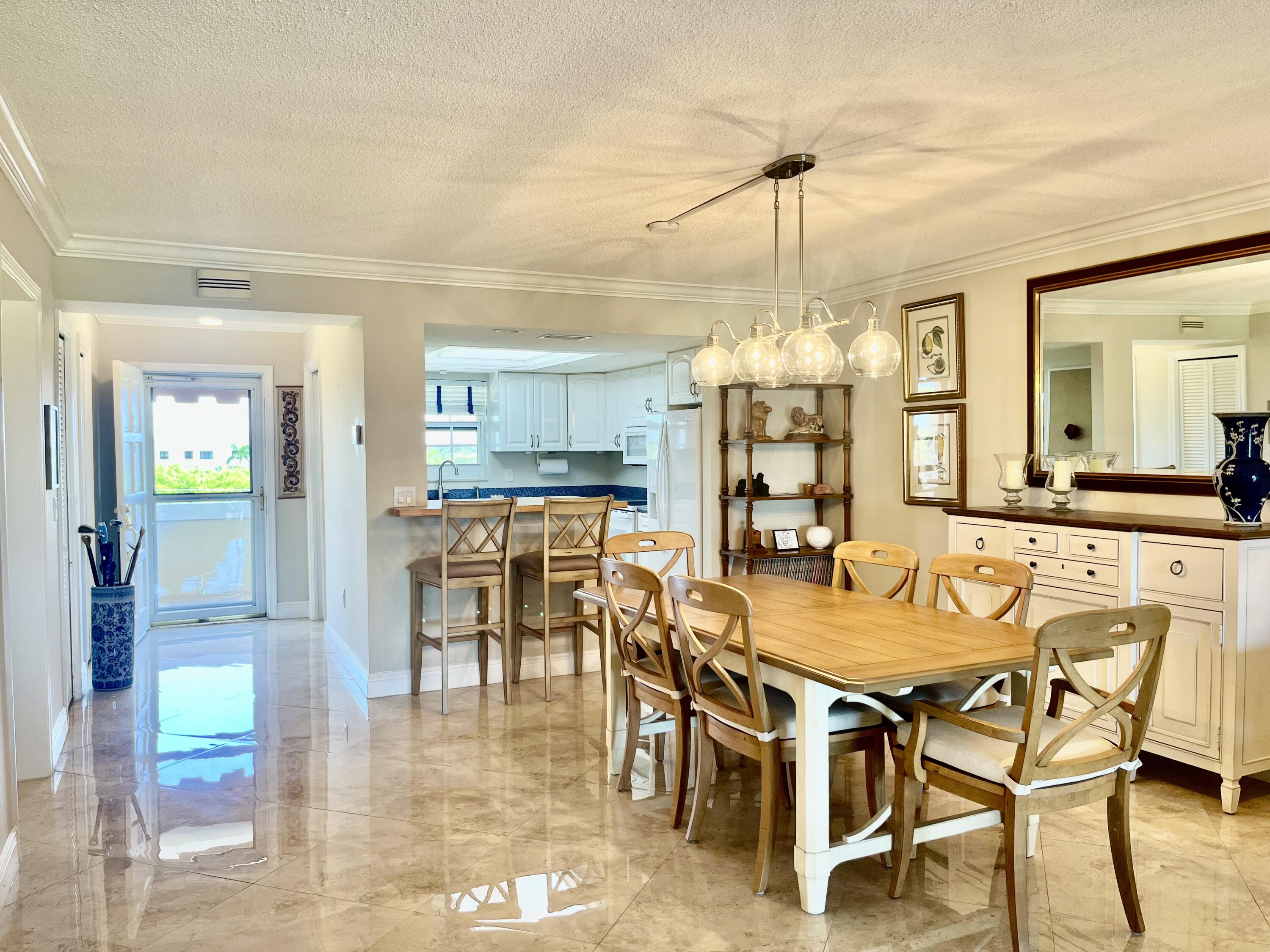 145 Atlantis Boulevard, Unit PH4 Atlantis, FL 33462 - Photo 8 of 27 a dining room with furniture a chandelier and kitchen view