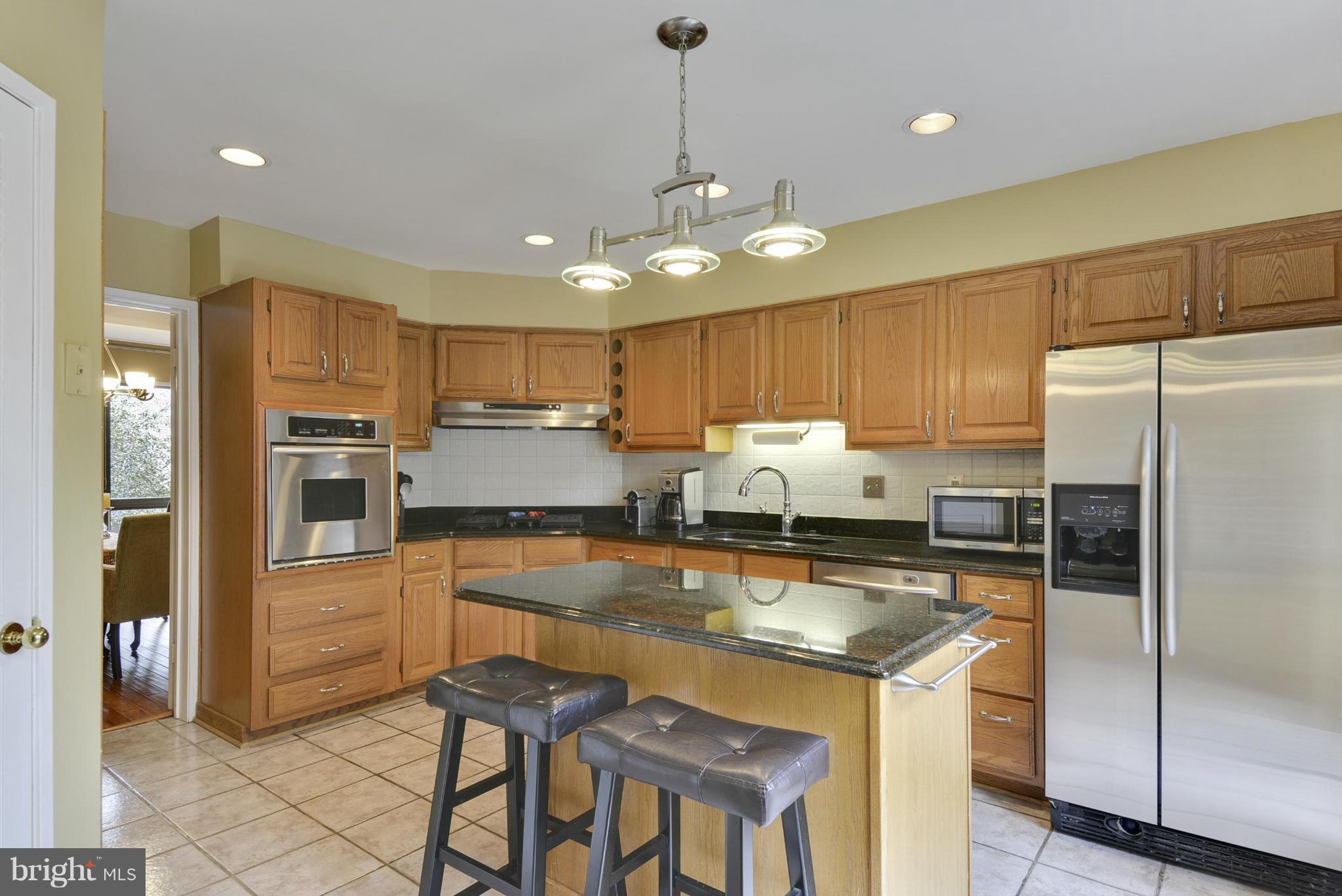 11706 Indian Ridge Road Reston, VA 20191 - Photo 3 of 30 a kitchen with kitchen island granite countertop white cabinets and stainless steel appliances