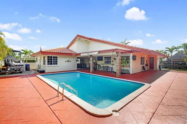 a view of pool with lawn chairs and potted plants