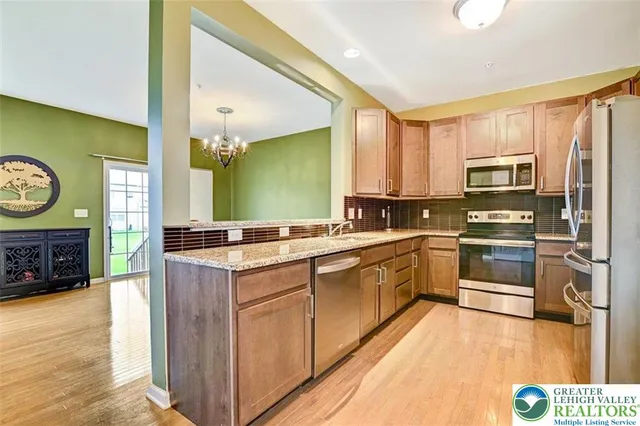a kitchen with stainless steel appliances granite countertop a stove top oven a sink and a refrigerator