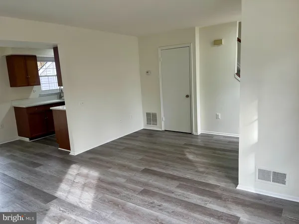 a view of an empty room with wooden floor and a fireplace