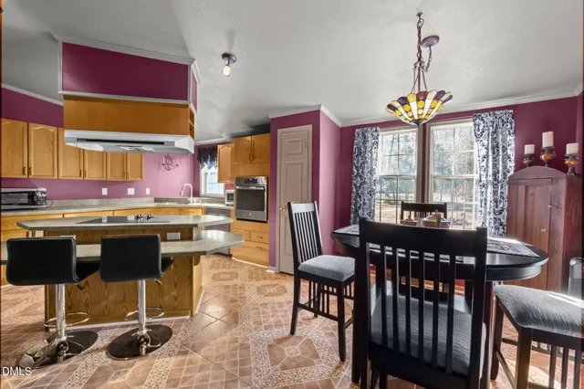 a kitchen with stainless steel appliances granite countertop a stove a refrigerator a kitchen island a dining table and chairs with wooden floor