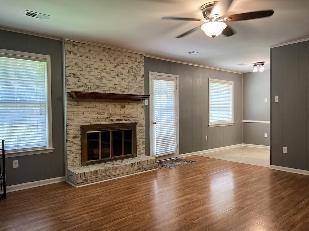 7935 Memphis Arlington Road Bartlett, TN 38133 - Photo 5 of 20 Living area featuring wood-finish flooring, a painted brick fireplace with a wood mantle, and a ceiling fan with integrated lighting