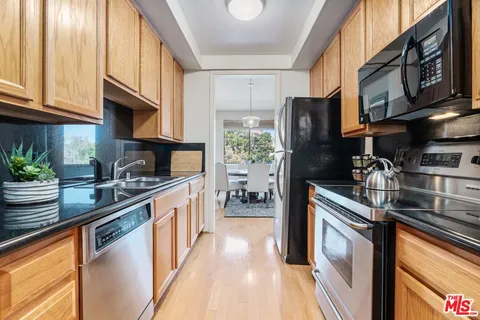 a kitchen with stainless steel appliances granite countertop a refrigerator a stove and a sink