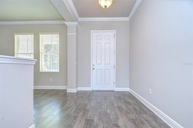 an empty room with wooden floor and windows