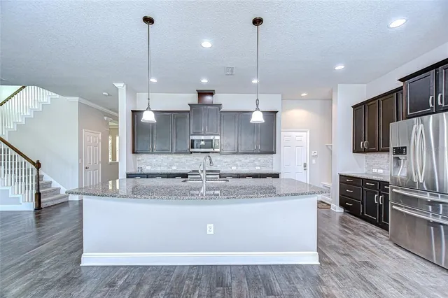 a kitchen with stainless steel appliances granite countertop counter space a sink refrigerator and cabinets