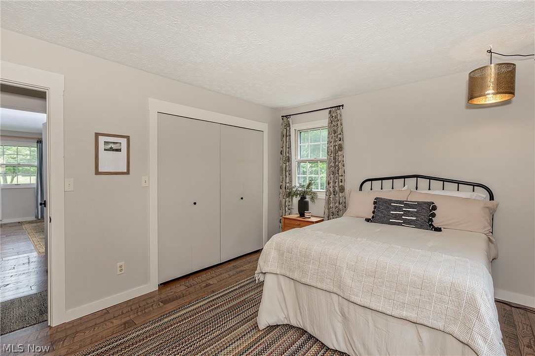 11292 Butternut Road Chardon, OH 44024 - Photo 27 of 49 Room featuring wood-finish flooring, a double window with black curtain rod, white baseboards, and a built-in closet with double doors