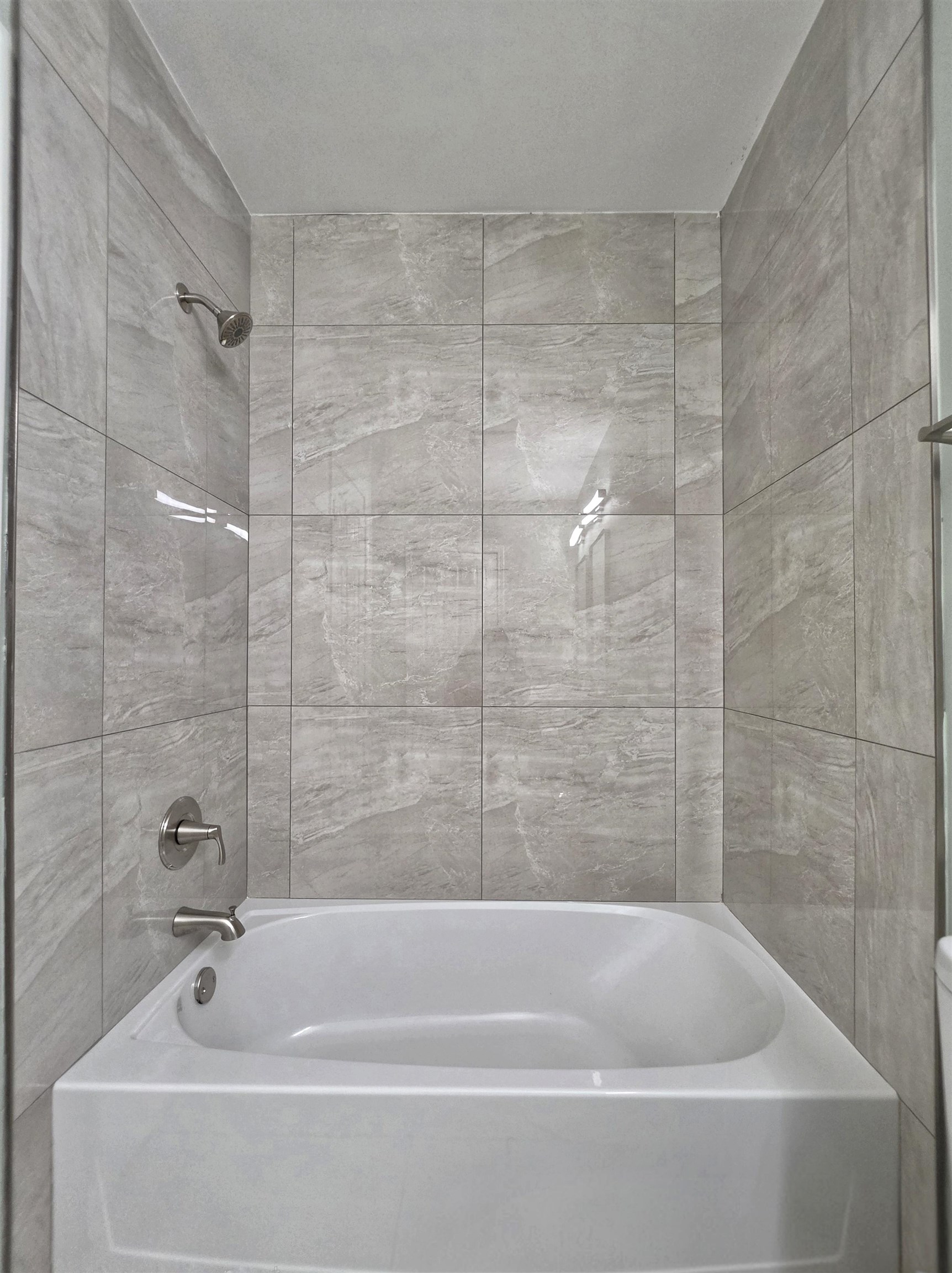 7966 Martha Road Millington, TN 38053 - Photo 17 of 26 White bathtub with brushed nickel fixtures, surrounded by large format grey tile walls