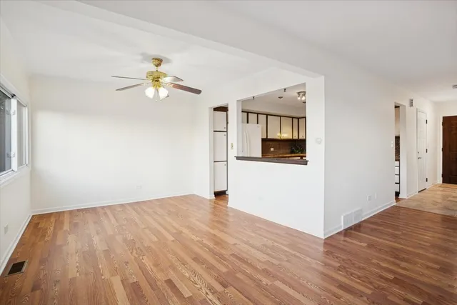 a view of empty room with wooden floor and ceiling fan