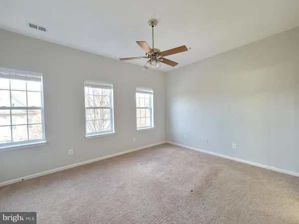 an empty room with windows and fan