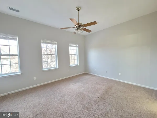 an empty room with windows and fan