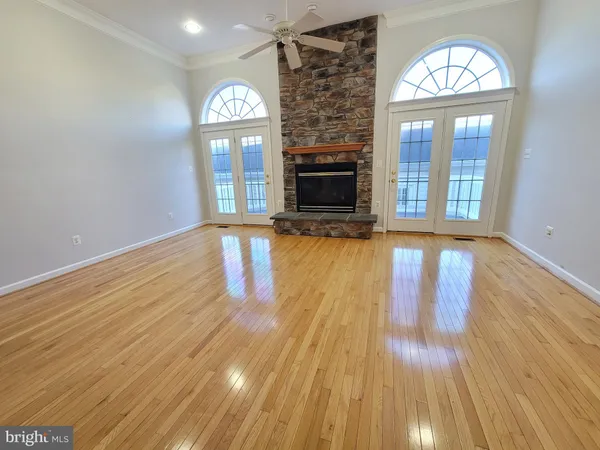 a view of an empty room with wooden floor fireplace and a window