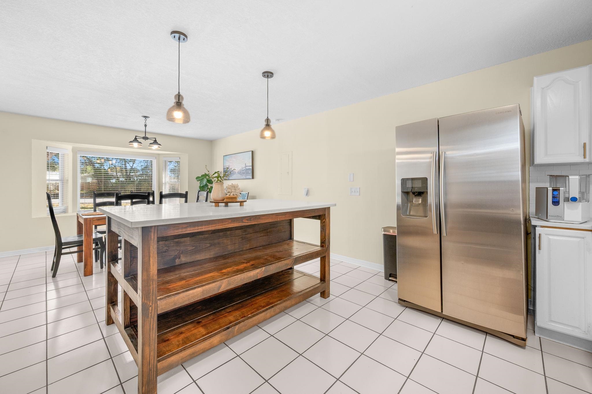 4233 Oak Lane St. Augustine, FL 32086 - Photo 20 of 42 Kitchen featuring stainless steel refrigerator with ice dispenser, white cabinetry, pendant lighting, light countertops, and light tile patterned flooring