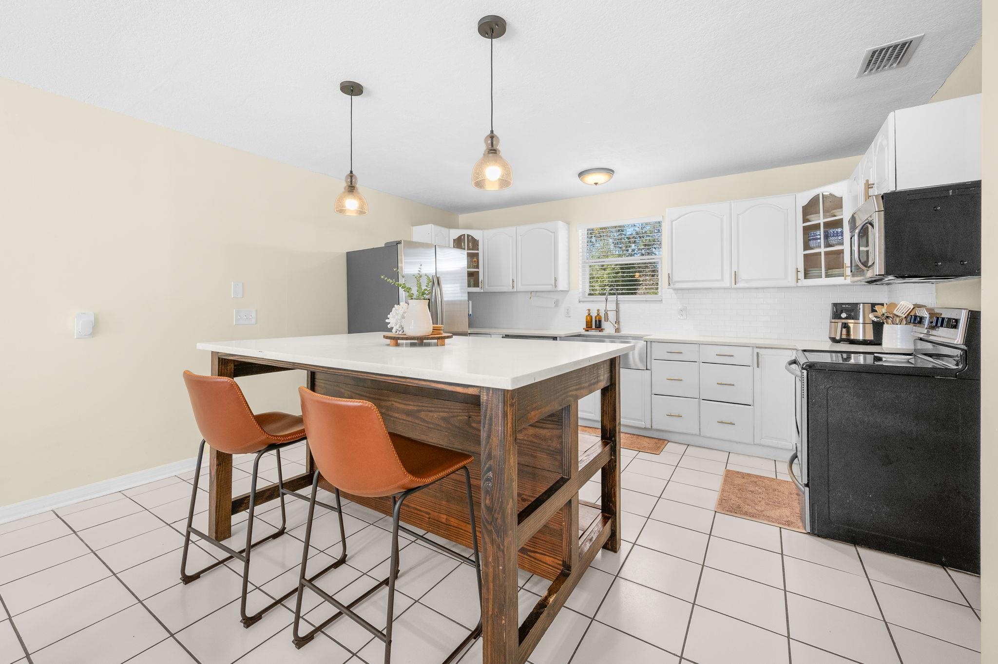 4233 Oak Lane St. Augustine, FL 32086 - Photo 23 of 42 Kitchen with glass fronted cabinets, white cabinetry, hanging light fixtures, stainless steel appliances, and backsplash