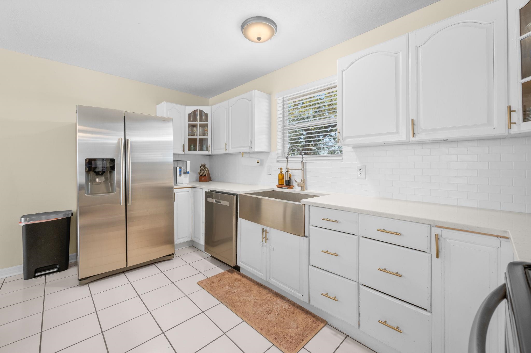 4233 Oak Lane St. Augustine, FL 32086 - Photo 24 of 42 Kitchen featuring glass fronted cabinets, stainless steel appliances, white cabinets, light tile patterned floors, and decorative backsplash