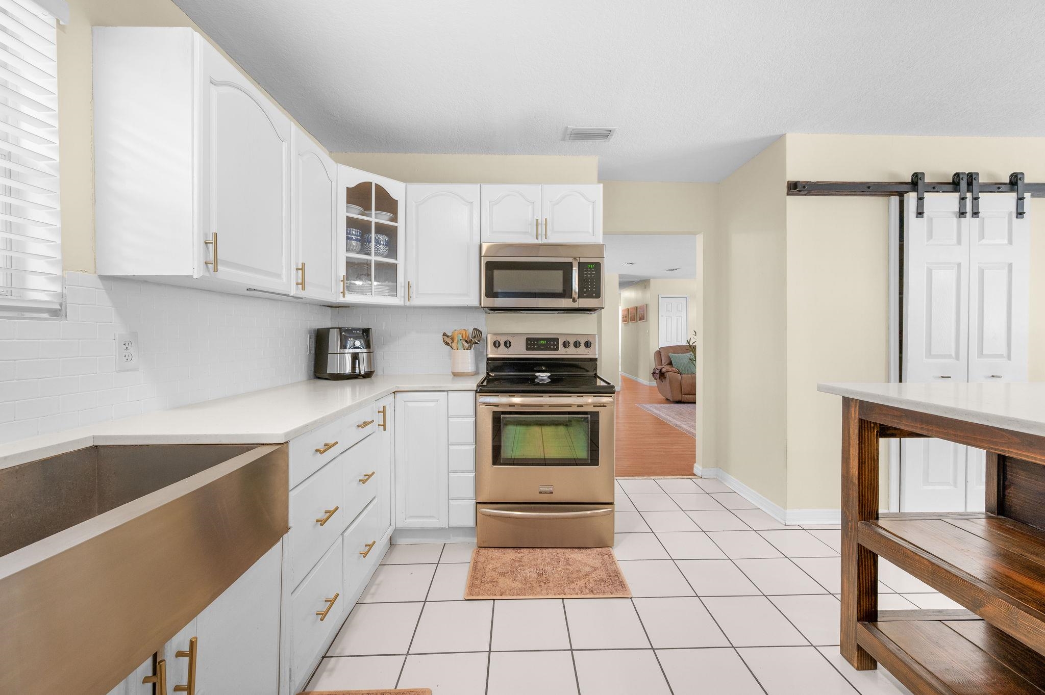 4233 Oak Lane St. Augustine, FL 32086 - Photo 25 of 42 Kitchen featuring stainless steel appliances, a barn door, white cabinetry, and glass fronted cabinets