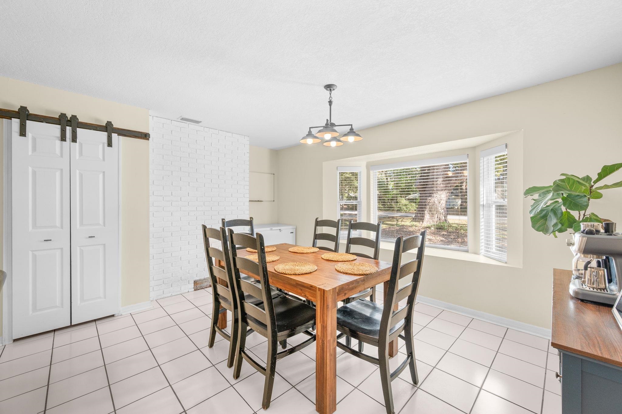 4233 Oak Lane St. Augustine, FL 32086 - Photo 27 of 42 Dining room with a barn door, light tile patterned flooring, and suspended lighting