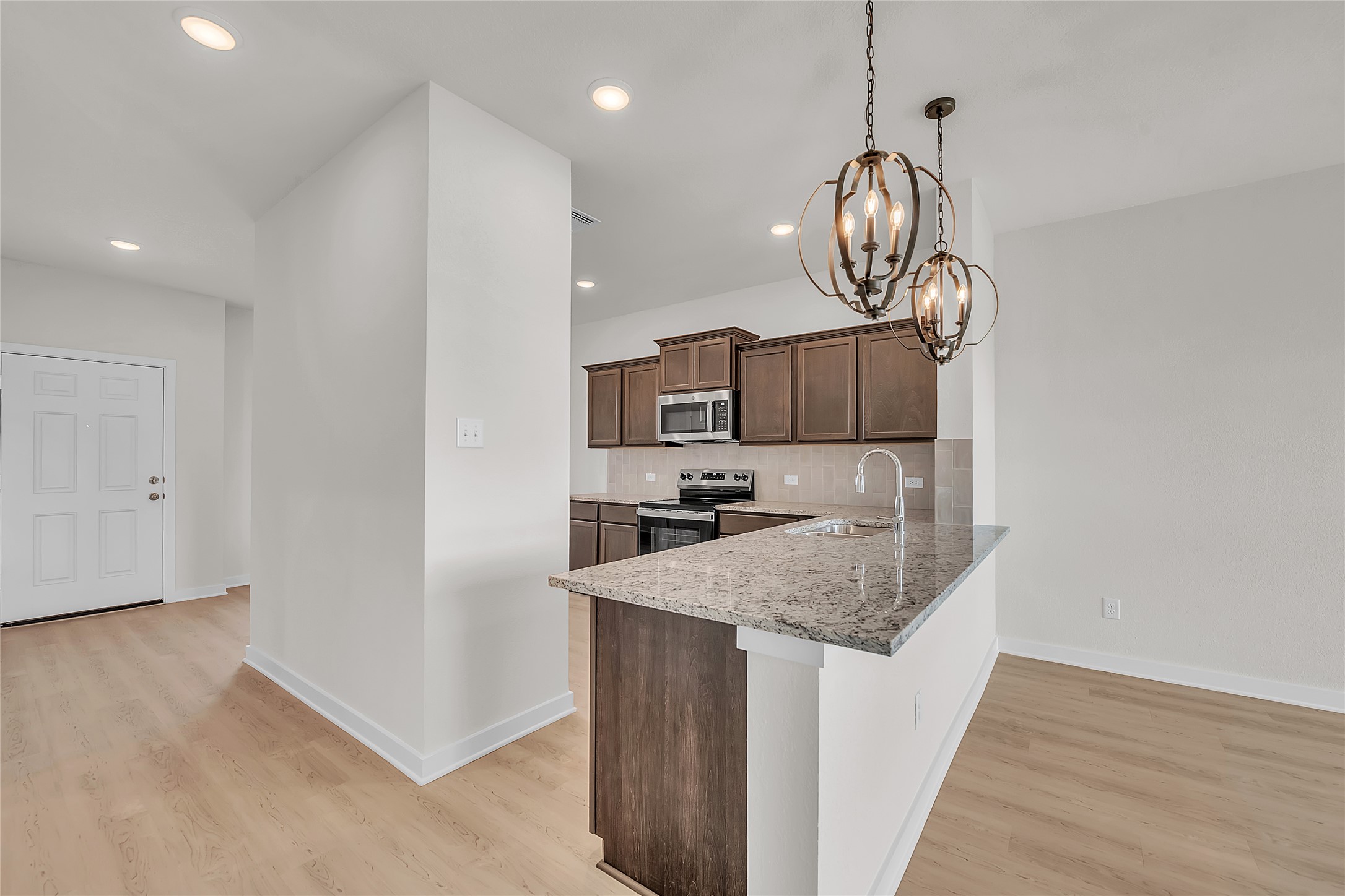 308 Boatright Boulevard Jarrell, TX 76537 - Photo 24 of 31 Kitchen featuring tasteful backsplash, stainless steel appliances, dark brown cabinetry, pendant lighting, and a chandelier