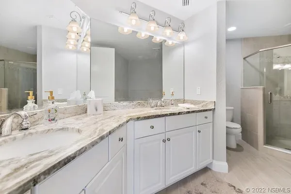 a bathroom with a granite countertop double vanity sink mirror and toilet