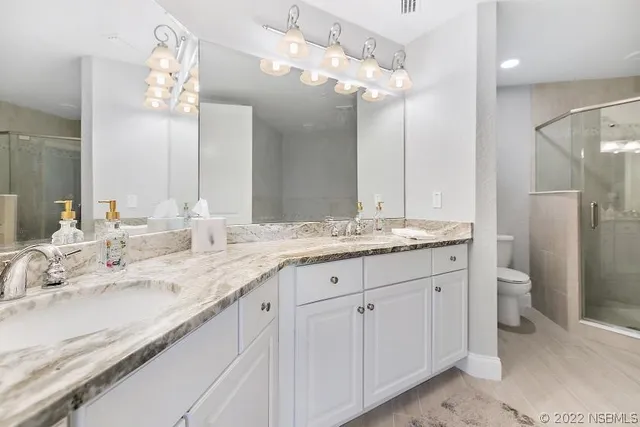 a bathroom with a granite countertop double vanity sink mirror and toilet