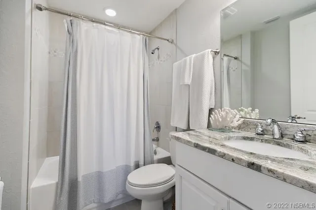 a bathroom with a granite countertop sink toilet and a mirror