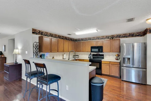 a kitchen with kitchen island a large counter top space appliances and wooden floor