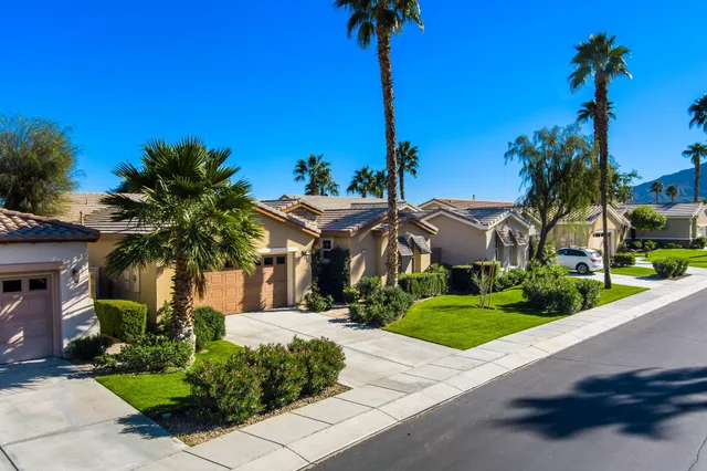 a front view of a house with a yard and palm trees