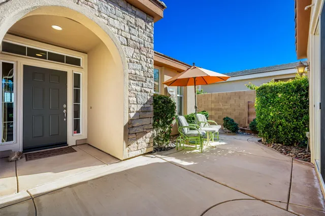 a backyard of a house with table and chairs under an umbrella