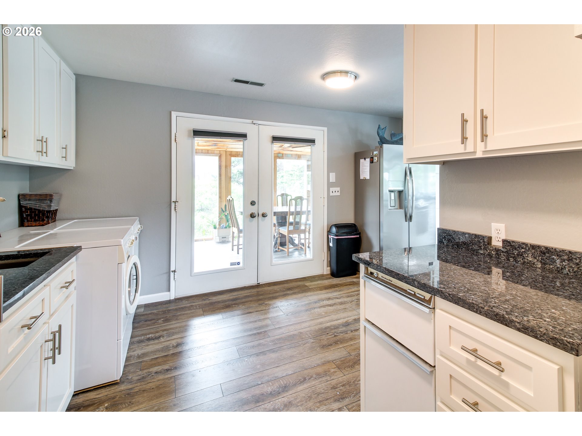 3085 Beach Loop Drive Southwest Bandon, OR 97411 - Photo 16 of 46 a kitchen with granite countertop a stove a sink and white cabinets with wooden floor