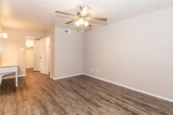 an empty room with wooden floor fan and windows