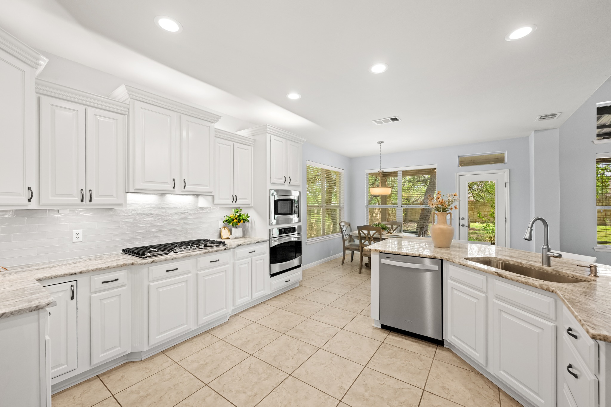 1023 Grassy Field Road Austin, TX 78737 - Photo 13 of 40 Spacious kitchen featuring white cabinetry, dolomitic marble countertops, tile flooring, stainless steel appliances, gas cooktop and concealed range hood.