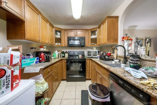 a kitchen with granite countertop lots of clutter and stainless steel appliances