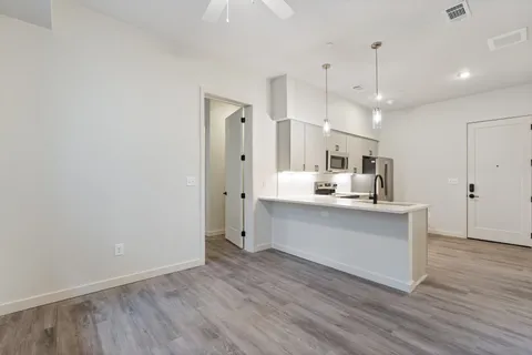 a large white kitchen with a refrigerator a sink dishwasher a oven and a large window with wooden floor