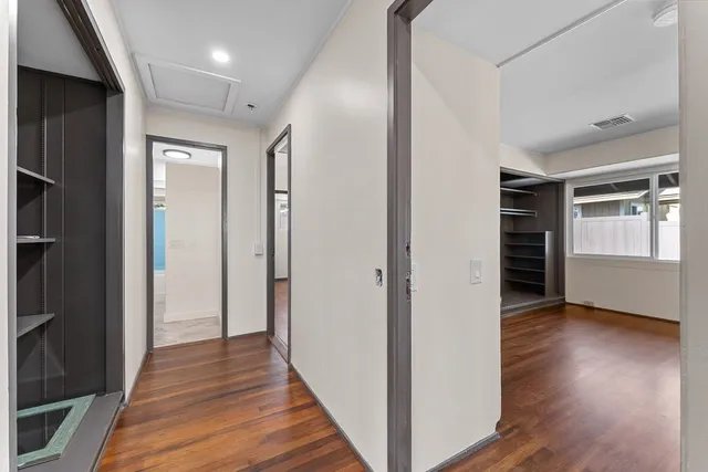 a view of empty room with wooden floor and fan
