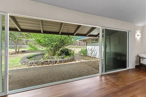 a view of a hallway with wooden floor and a living room