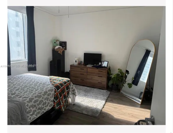 a bedroom with a bed and a flat tv screen on dresser