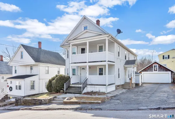 a view of a white house next to a road and yard