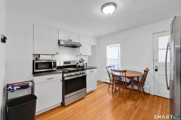 a kitchen with stainless steel appliances kitchen island granite countertop a refrigerator a stove a dining table and chairs