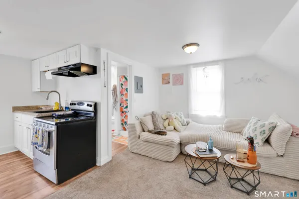 a living room with furniture and a refrigerator