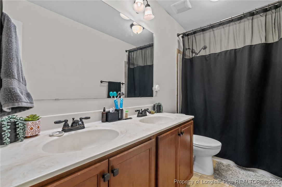 182 Valley Stream Road Spring Lake, NC 28390 - Photo 18 of 26 a bathroom with a sink a toilet and mirror