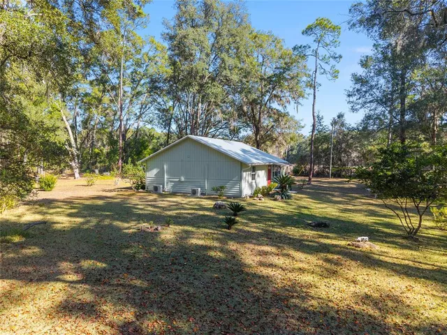a view of a house with a yard and a large tree
