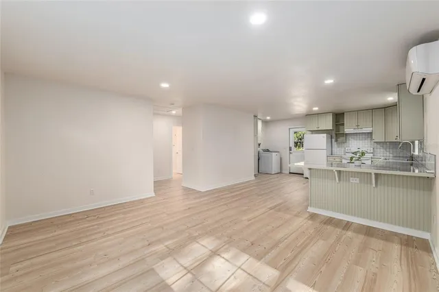 a view of a kitchen with kitchen island a sink wooden floor and a refrigerator