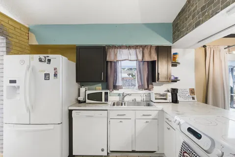 a kitchen with white cabinets and refrigerator