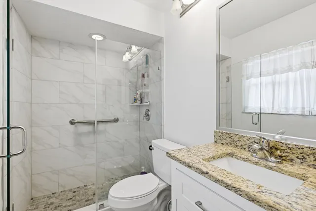 a bathroom with a granite countertop sink a toilet and shower