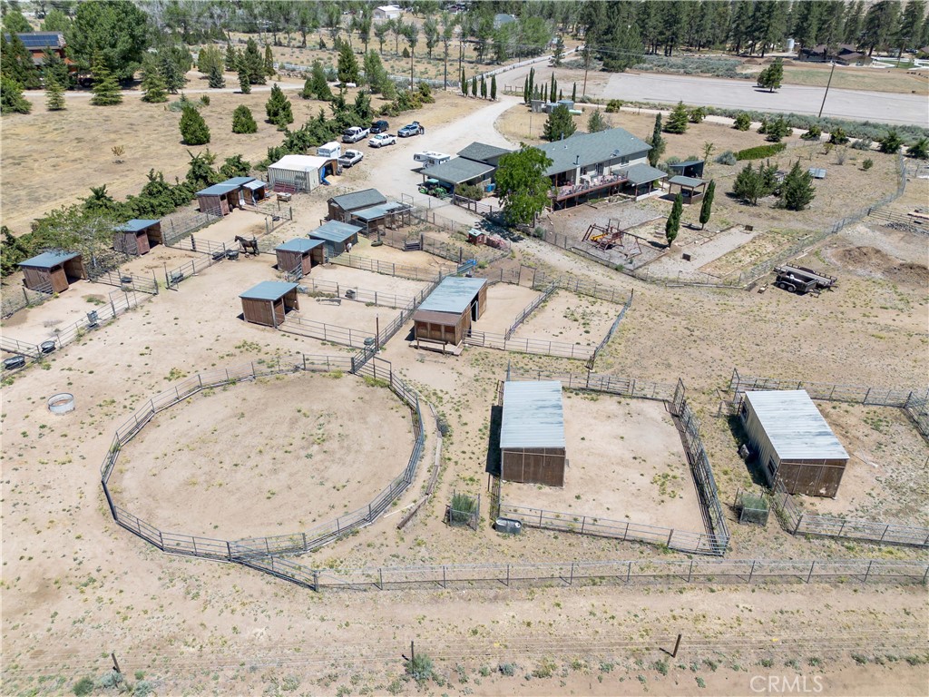 10960 Steinhoff Road Frazier Park, CA 93225 - Photo 5 of 46 An elevated aerial perspective showcasing the equestrian facilities, highlighted by a large fenced round pen, multiple covered horse stalls, open turnouts, and a clear view of the surrounding property landscape.
