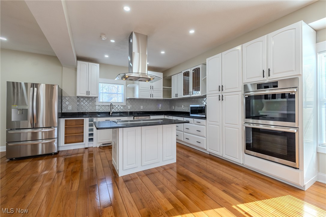 3516 Broadview Road Cleveland, OH 44109 - Photo 11 of 42 Kitchen featuring open shelves, island exhaust hood, appliances with stainless steel finishes, dark countertops, and light wood-type flooring