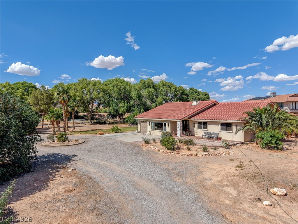 1950 Bowman Road Logandale, NV 89021 - Photo 71 of 81 A terracotta tile roof crowns this desert oasis, surrounded by lush trees and a wide-open gravel driveway.