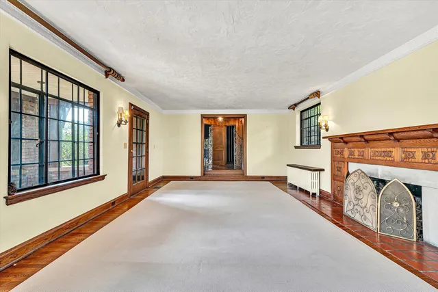 an empty room with wooden floor fireplace and windows