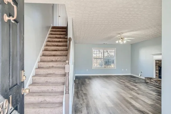 a view of an empty room with wooden floor and window