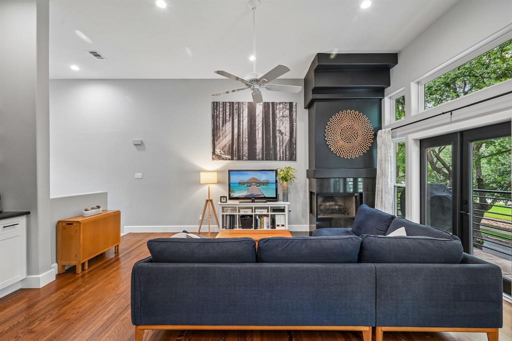 3553 Wheeler Street Dallas, TX 75209 - Photo 7 of 35 Vaulted ceiling living room with fireplace, hardwood floors, and wall of windows overlooking mature trees near Oak Lawn